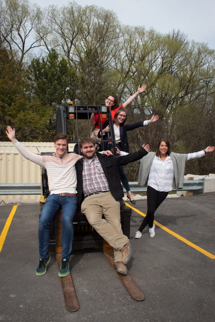A group of students standing on an isowater forklift outside in the company parking lot