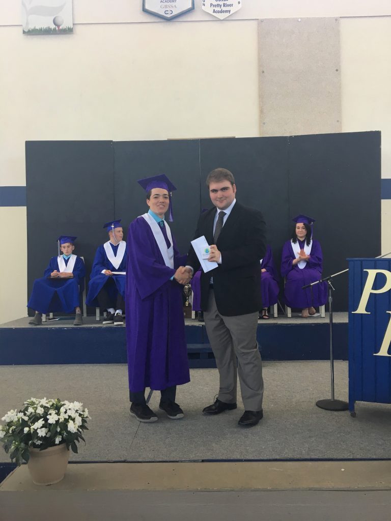 A student receiving their diploma from a presenter 